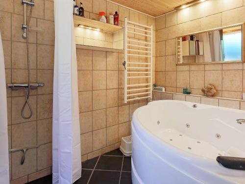 a bathroom with a tub and a shower with a mirror at 6 person holiday home in Gilleleje in Gilleleje