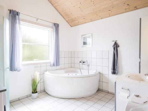 a white bathroom with a tub and a window at Secluded Cozy Cottage in Skaven-By Traum in Tarm