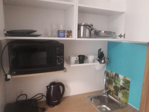 a small kitchen with a sink and a microwave at Sol De Sopot in Sopot