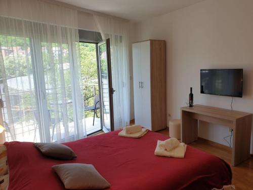 Schlafzimmer mit einem großen Bett mit roter Bettwäsche und einem TV in der Unterkunft Happy in Vrnjačka Banja