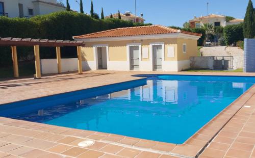 a swimming pool in front of a house at Apartamento piscina 5 minutos praia in Alcantarilha