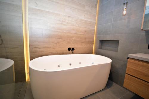 y baño con bañera blanca y paredes de madera. en Wintergreen 10, en Thredbo