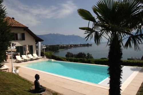 a man sitting next to a swimming pool next to a house at Corseaux Beach rooms-Riviera Beach apartments in Vevey