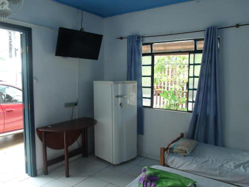 a room with a refrigerator and a table and a window at Pousada Edson in Caraguatatuba