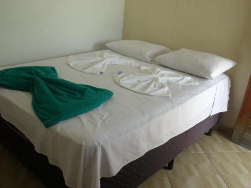 a bed with white sheets and pillows on it at Pousada Edson in Caraguatatuba