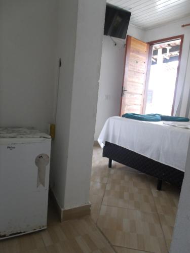 a bedroom with a bed and a window and a television at Pousada Edson in Caraguatatuba