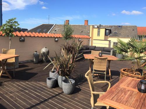 a patio with wooden tables and chairs and plants at City Hotel Nattergalen in Odense