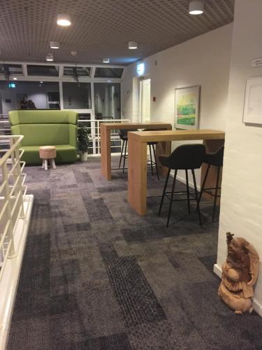 a room with tables and chairs and a green couch at City Hotel Nattergalen in Odense
