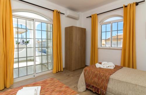 a bedroom with yellow curtains and a bed and a large window at Albuera Villa in Albufeira