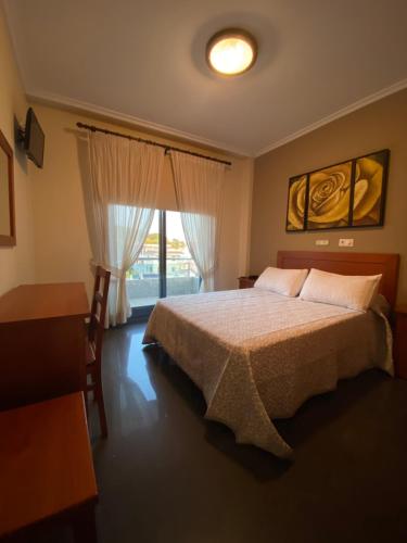 a bedroom with a large bed and a window at Hotel Pedramar in A Lanzada
