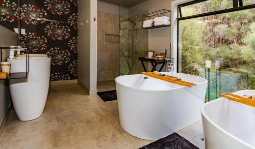 een badkamer met 2 wastafels, een bad en een douche bij Night Sky Cottage in Ohakune