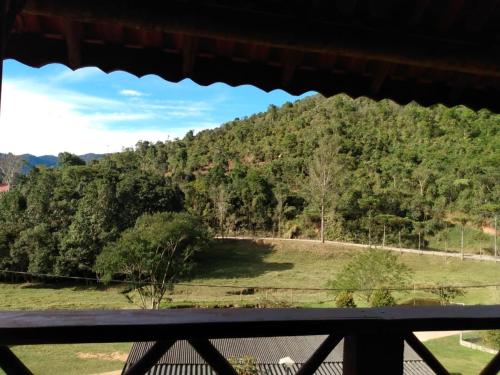 a view of a hill with a field and trees at POUSADA BELA HELENA in Visconde De Maua