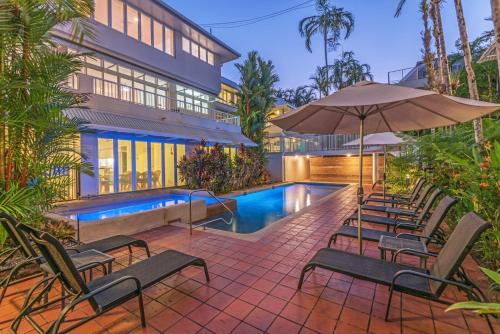 
a patio area with tables, chairs and umbrellas at Balboa Apartments in Port Douglas
