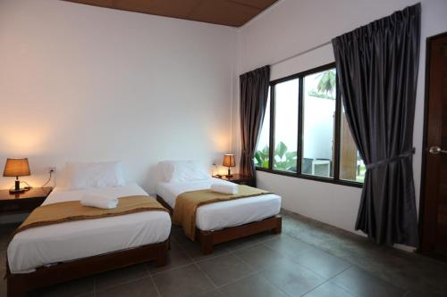 Rafflesia Resort في Lundu: غرفة نوم بسريرين ونافذة كبيرة