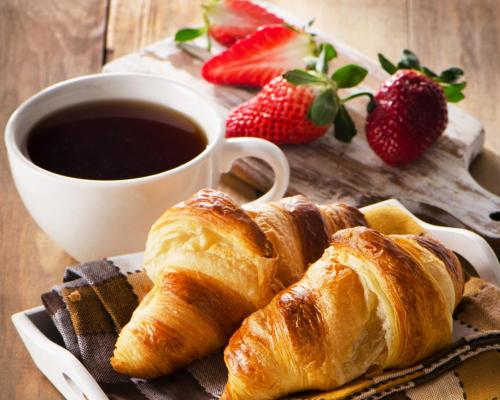 a plate of croissants and a cup of coffee and strawberries at Afalina Hotel in Khabarovsk