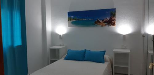a small bedroom with a bed with blue pillows at Apartamento Junto a El Corte Inglés Algeciras 2 in Algeciras