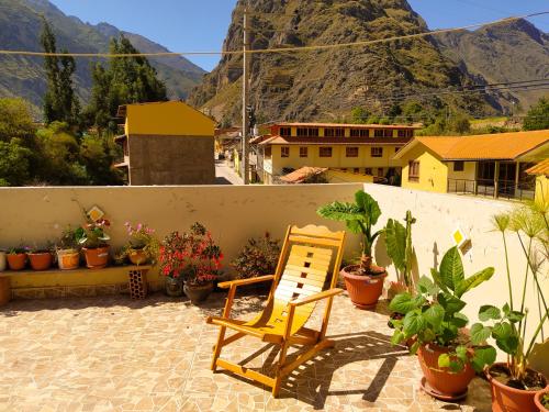 einem gelben Stuhl auf einer Terrasse mit Topfpflanzen in der Unterkunft Tambo de Ollantay Hotel in Ollantaytambo