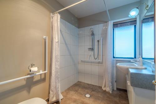 a bathroom with a shower and a toilet and a sink at Fantail Cottage with Sea Views - Akaroa Home in Akaroa