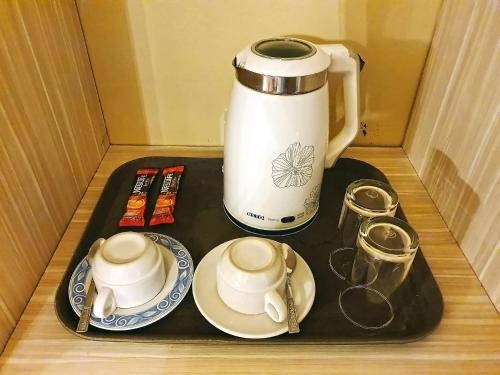 a tray with cups and plates and a coffee pot at The Montana Lodge-Sathorn in Bangkok