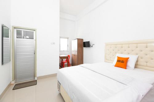 ein Schlafzimmer mit einem großen weißen Bett und einem orangefarbenen Kissen in der Unterkunft RedDoorz @ Losari Area 2 in Makassar