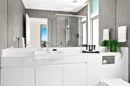 a white bathroom with a sink and a mirror at Argo Apartments in Wollongong
