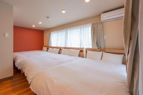 two large beds in a room with a window at VILLA KOSHIDO KOTONI annex in Sapporo