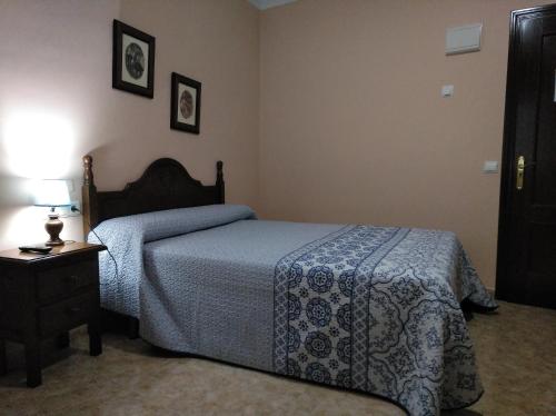 um quarto com uma cama e uma mesa com um candeeiro em Hostal El Polígono em Lucena