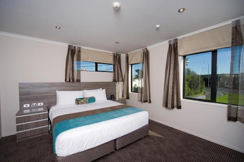 a bedroom with a bed and a large window at Best Western Ellerslie International Hotel in Auckland