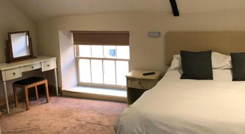 a bedroom with a bed and a mirror and a window at Oakham Hotel in Oakham