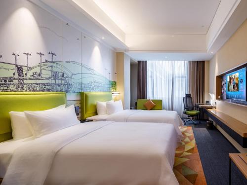 a hotel room with two beds and a desk at Hampton by Hilton Guangzhou Baiyun Airport North in Huadu