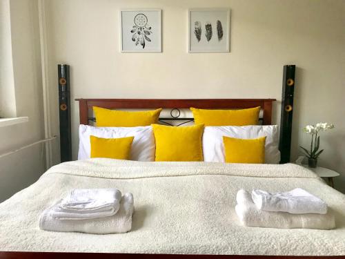 a bedroom with a bed with yellow pillows and towels at Moderný Byt Pri Pešej Zóne in Martin