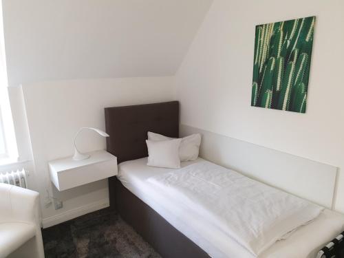 een kleine slaapkamer met een wit bed en een groen schilderij bij Villa zur schönen Aussicht in Bad Salzuflen