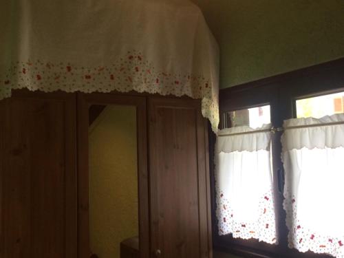 a room with two windows with curtains and a mirror at ΕΞΟΧΙΚΗ ΚΑΤΟΙΚΙΑ ΕΥΑΓΓΕΛΙΑ in Pávliani