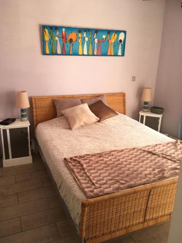 1 dormitorio con 1 cama grande de mimbre y 2 mesas en VILLA 800 MÈTRES DE LA PLAGE, en Andernos-les-Bains