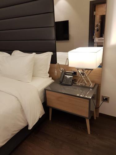 a hotel room with a bed and a table with a phone at Swiss-Belboutique Bneid Al Gar Kuwait in Kuwait