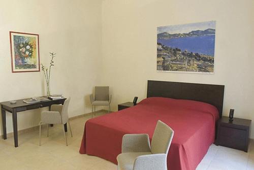 um quarto com uma cama vermelha, uma mesa e cadeiras em Palazzo Serraino em Trapani