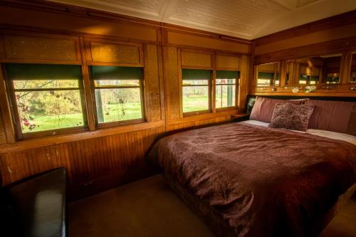 1 dormitorio con 1 cama y 2 ventanas en Carriages Spa Retreat en Echuca