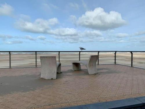 two benches sitting on a pier near the beach at Apartment Hertstraat in Ostend