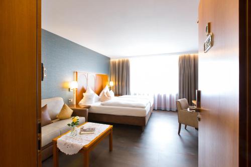 a hotel room with a bed and a couch at AKZENT Hotel Restaurant Altdorfer Hof in Weingarten
