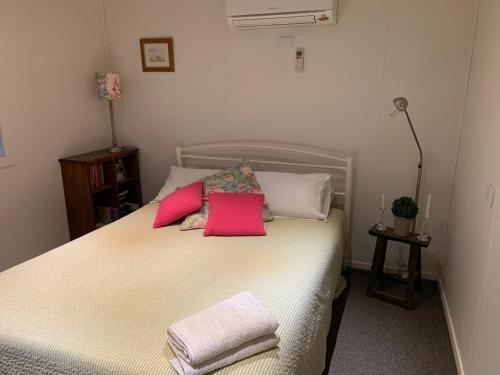 una camera da letto con un letto con cuscini rosa di Mascot Cottage - Pet Friendly and Complimentary Breakfast Hamper a West Wyalong