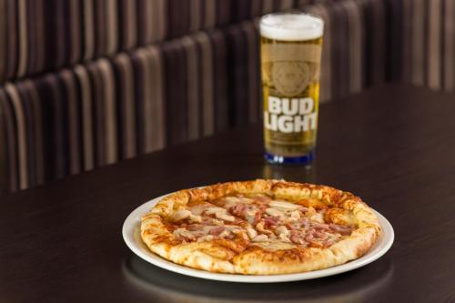 a pizza on a plate next to a glass of beer at Holiday Inn Express Lincoln City Centre by IHG in Lincoln