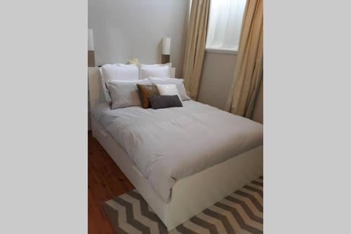 Una cama con sábanas blancas y almohadas en un dormitorio en Gawler Heritage Accommodation, en Gawler
