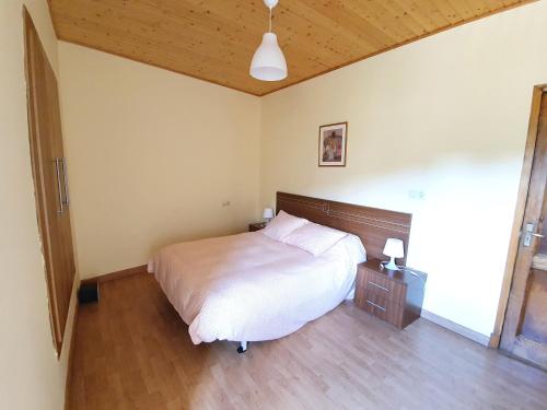 a bedroom with a white bed and a wooden floor at Casa García in Allariz