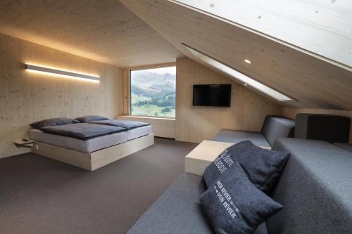 a room with two beds and a tv and a couch at Revier Mountain Lodge Adelboden in Adelboden