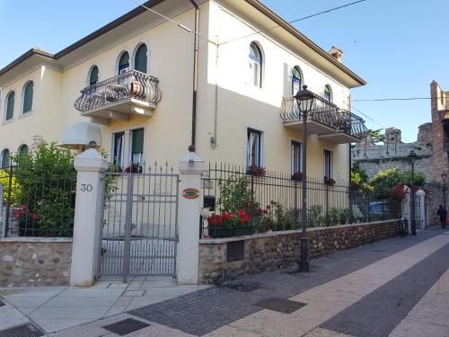 a white house with two balconies and a fence at Hotel Villa Cansignorio in Lazise