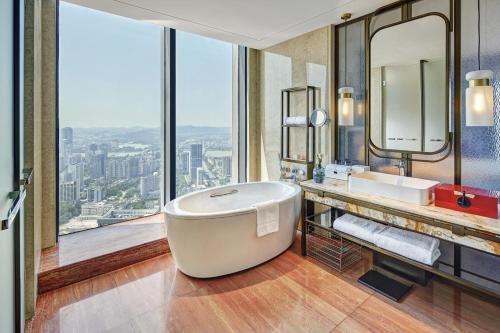 a bathroom with a tub and a large window at Pullman Huizhou Kaisa in Huizhou