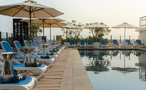 una fila di sedie e ombrelloni accanto alla piscina di HARI Residence & Spa a Siem Reap