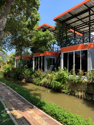 a building with a pond in front of it at Meephawa Resort in Amphawa