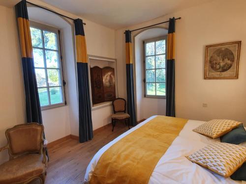 a bedroom with a large bed and two windows at Manoir du Bellay in Montreuil-Bellay