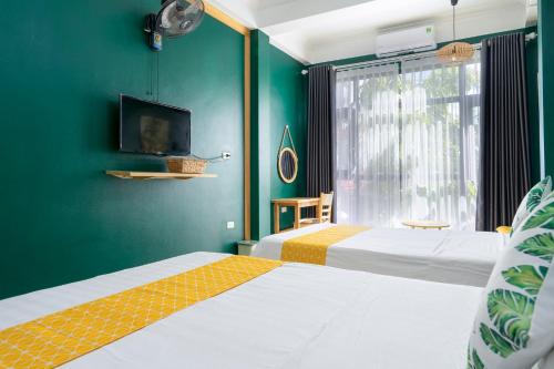 two beds in a room with green walls at VietHouse Homestay Ha Long in Ha Long
